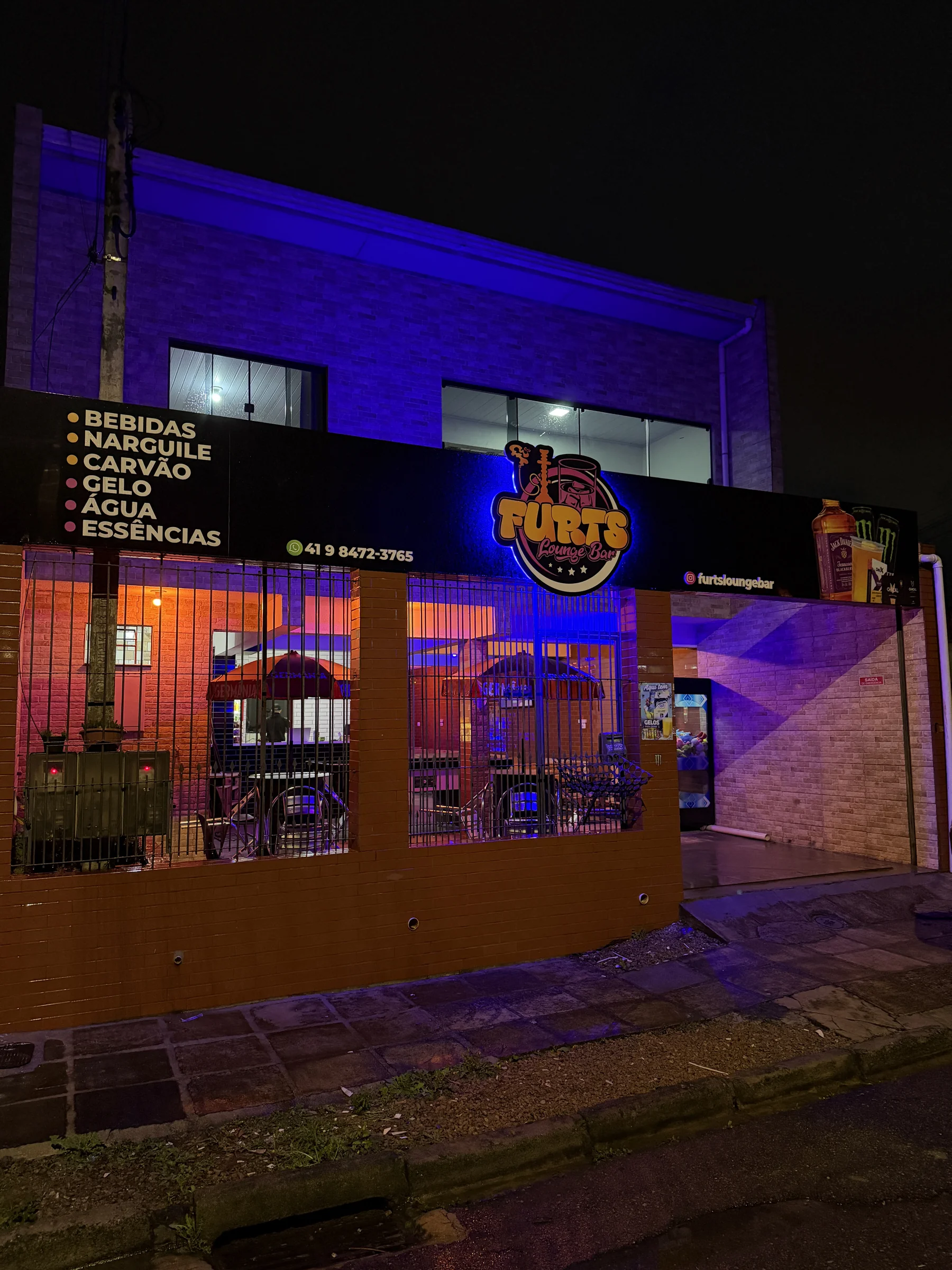 Fachada da Furts Lounge Bar iluminada em roxo, no Campo de Santana, Curitiba